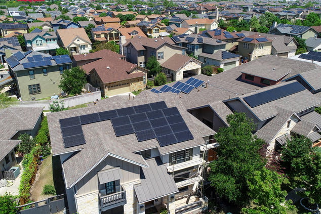 Güneş enerjisi yenilenebilir enerji kaynağıdır, evlerin çatılarında güneş panelleri olan görsel.